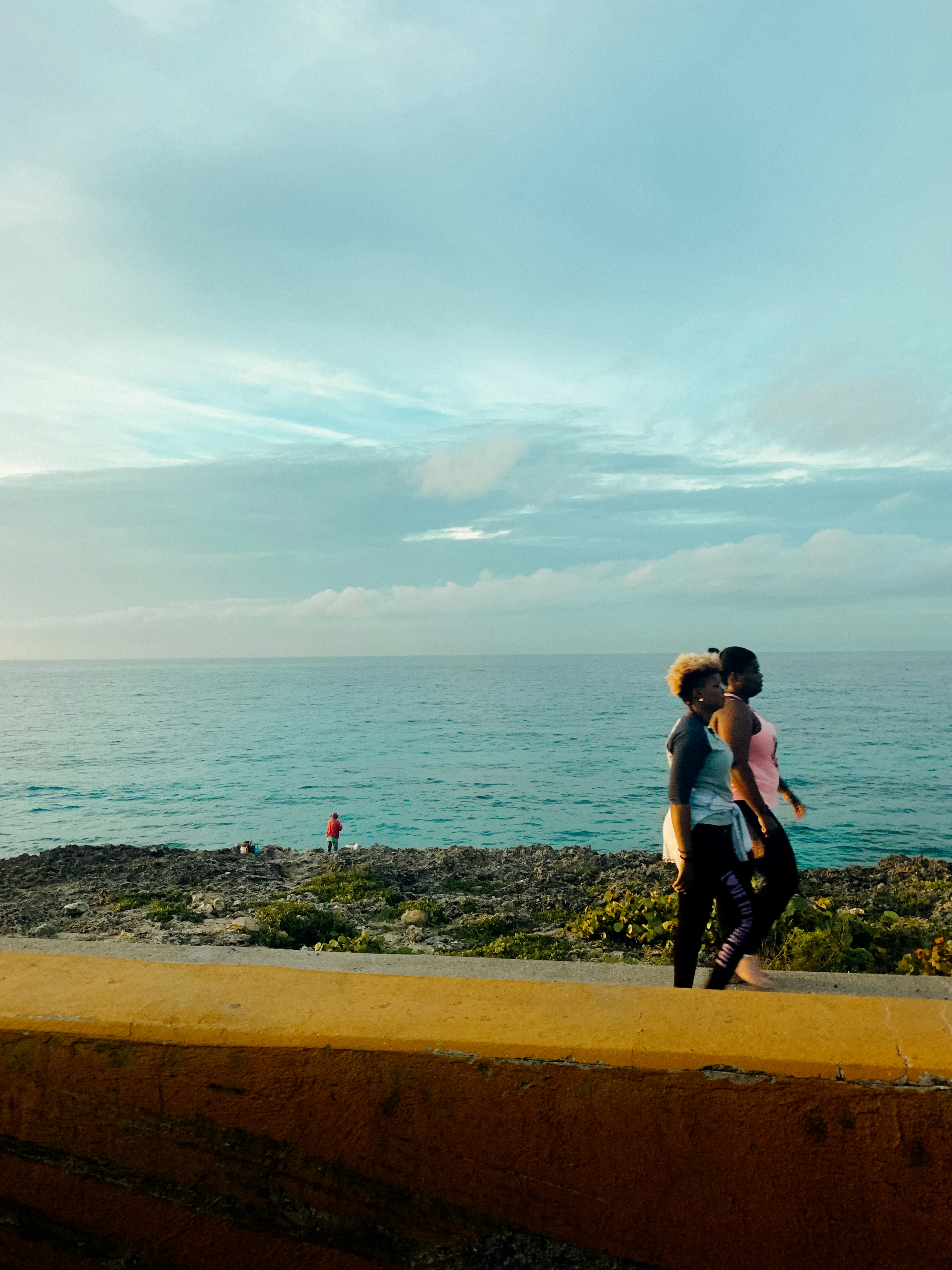 a man and woman standing on a ledge overlooking a body of water