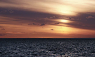 A serene tropical sunset over calm ocean waters with soft golden light.
