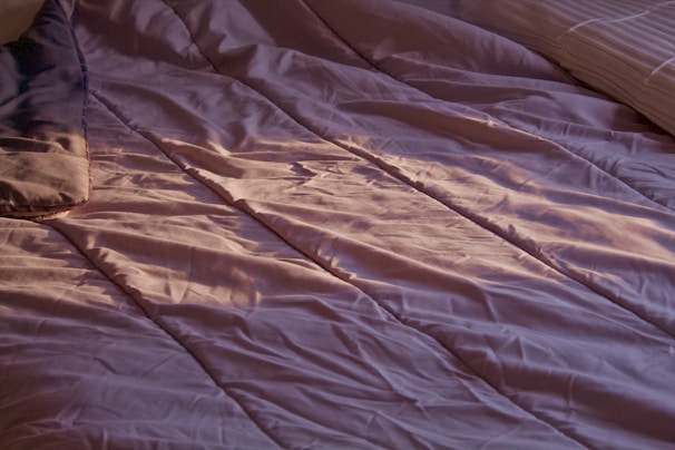 Close-up of smooth pastel blue Luxora bedsheets with delicate folds catching the morning light gently.