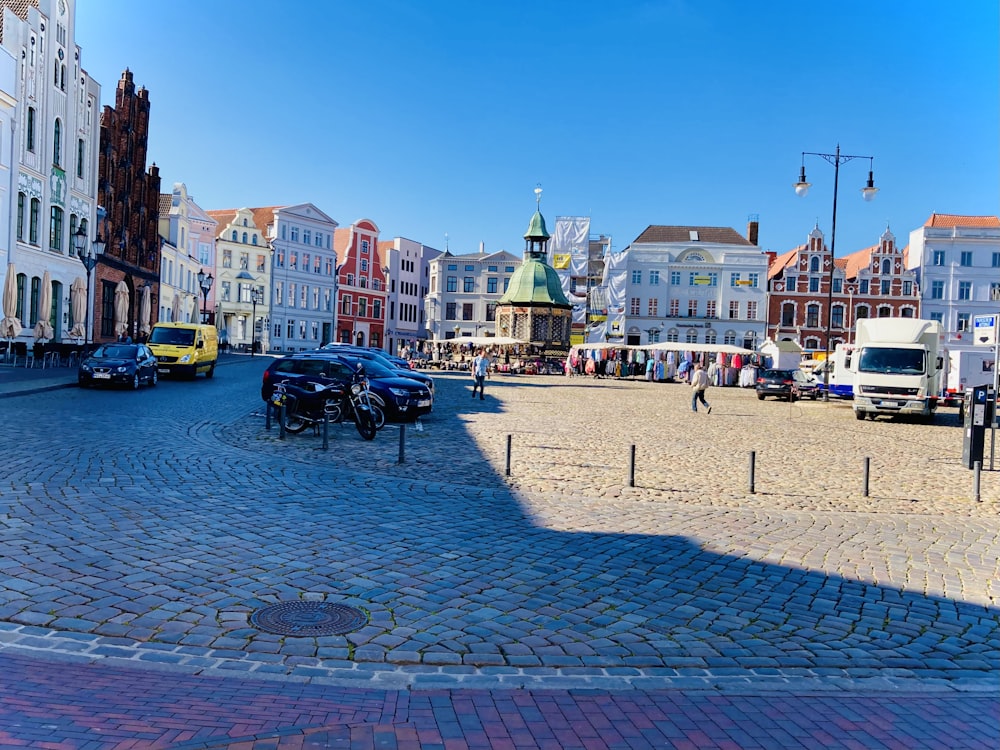 a brick road with cars and buildings on either side of it