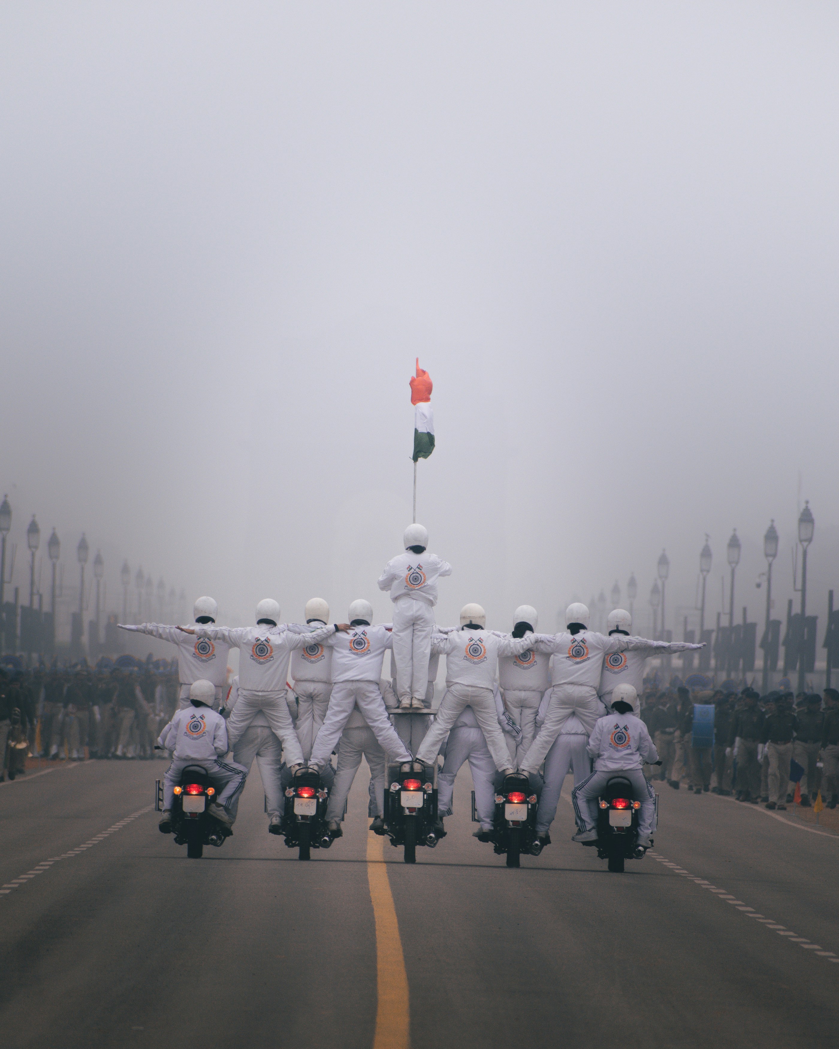 a group of people in white suits on motorcycles on a road