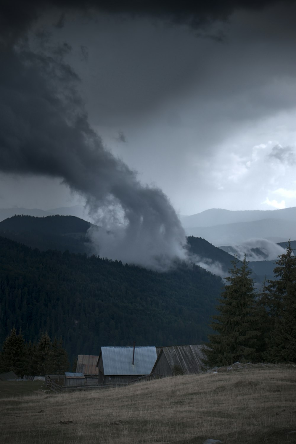 a building with smoke coming out of it and a mountain in the background