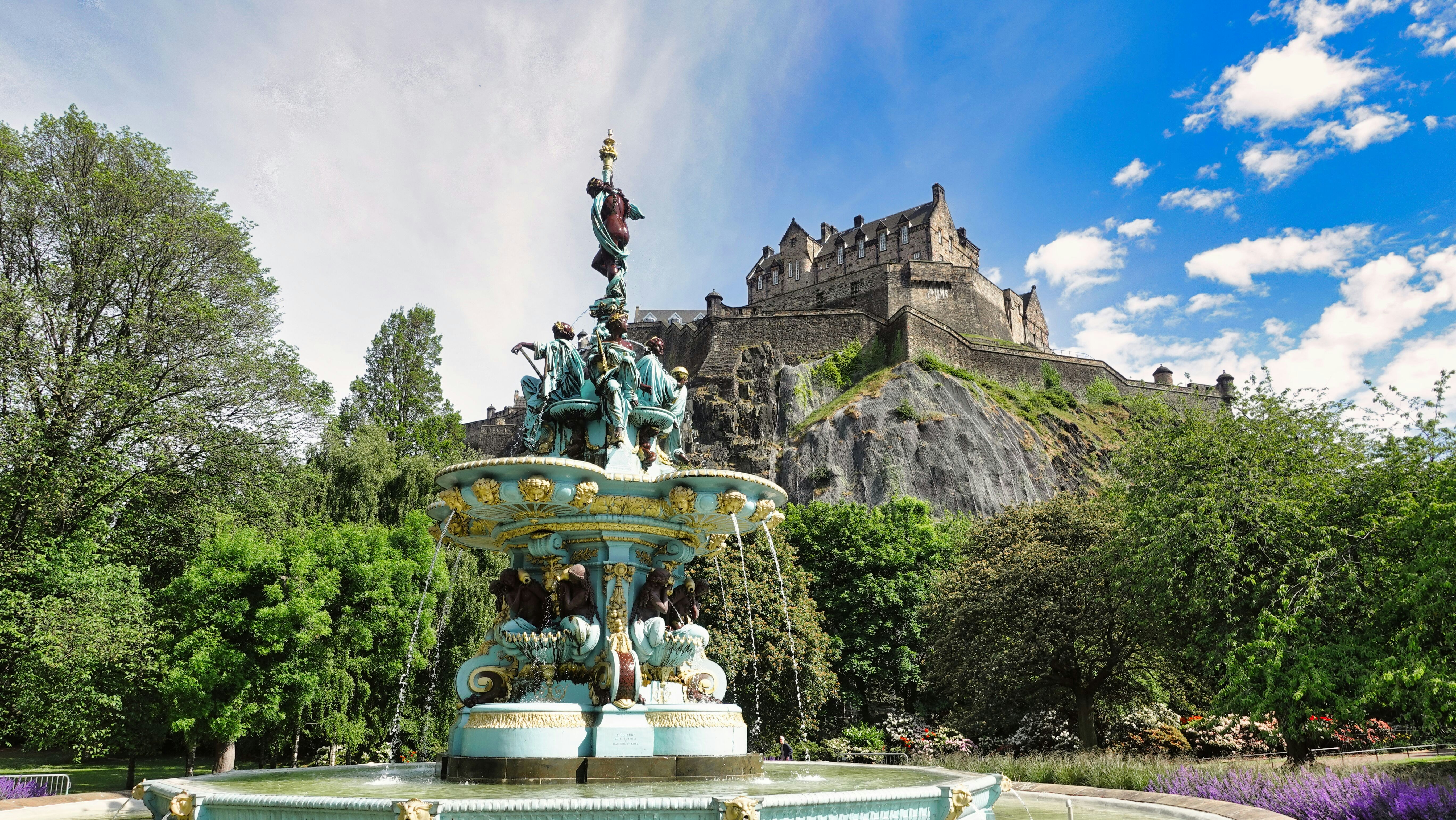 a fountain with statues and trees in the background