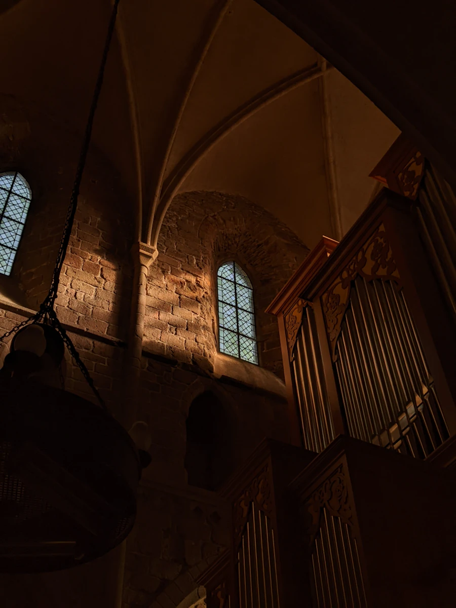 Stone arches and a high window inside a candlelit old church