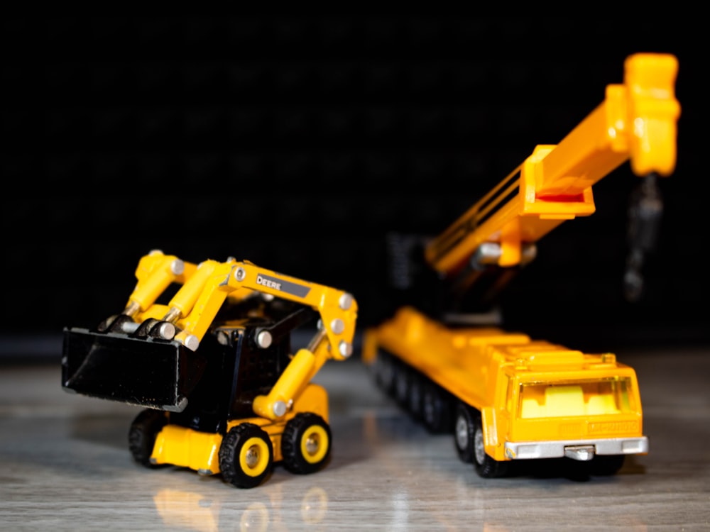 a yellow construction vehicle next to a black and yellow construction vehicle