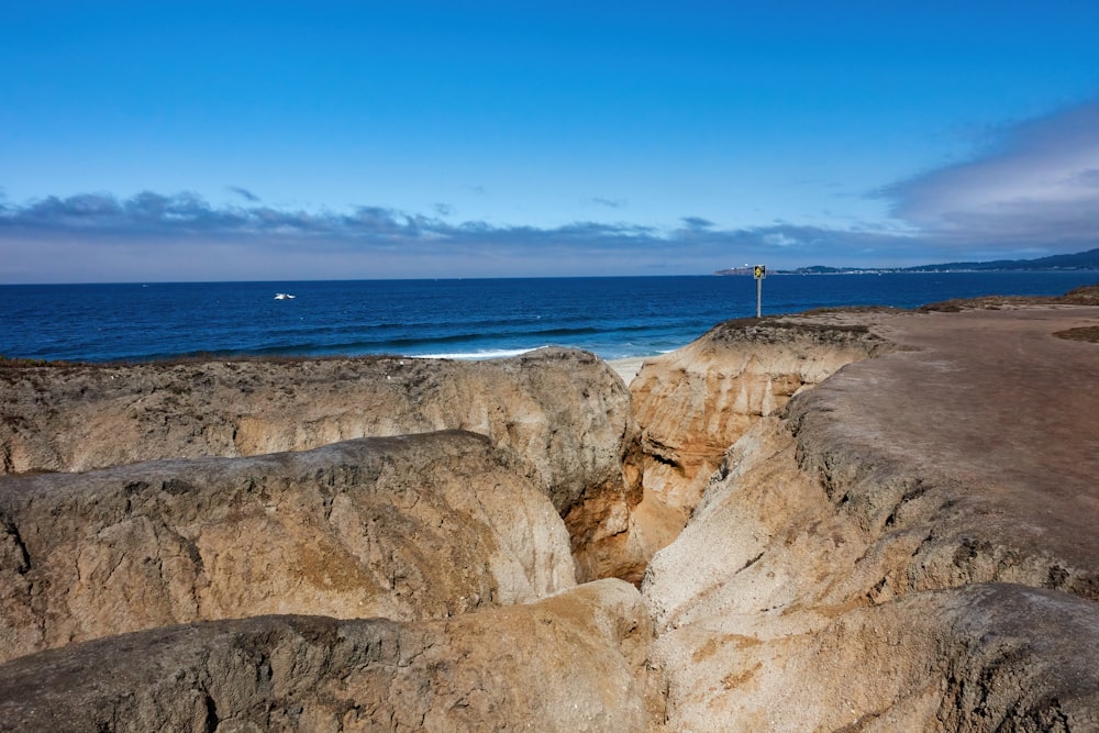 a rocky beach with a body of water in the background