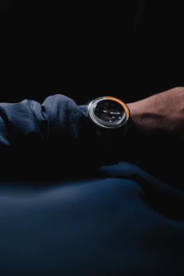 Close-up of a man adjusting a sleek watch against a dark background.