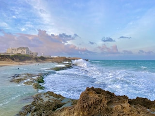 a rocky beach with a building in the background