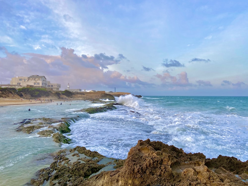 a rocky beach with a building in the background