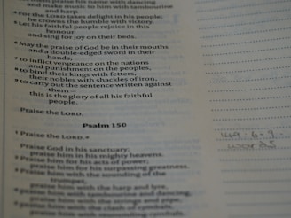 Text from a religious scripture is displayed on a page. It includes verses and appears to be a part of Psalm 149 and 150. There are printed lines alongside handwritten notes at the bottom.