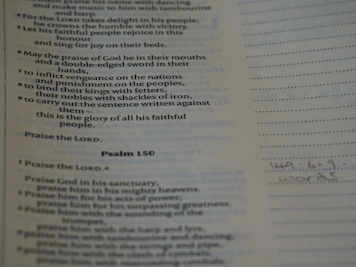 Text from a religious scripture is displayed on a page. It includes verses and appears to be a part of Psalm 149 and 150. There are printed lines alongside handwritten notes at the bottom.