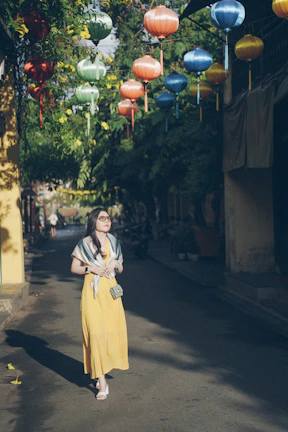 A relaxed woman in a colorful dress walking through a sunlit urban street