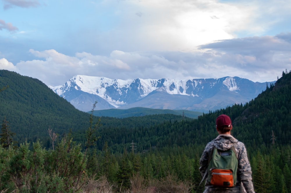 a man standing in a forest with a mountain in the background