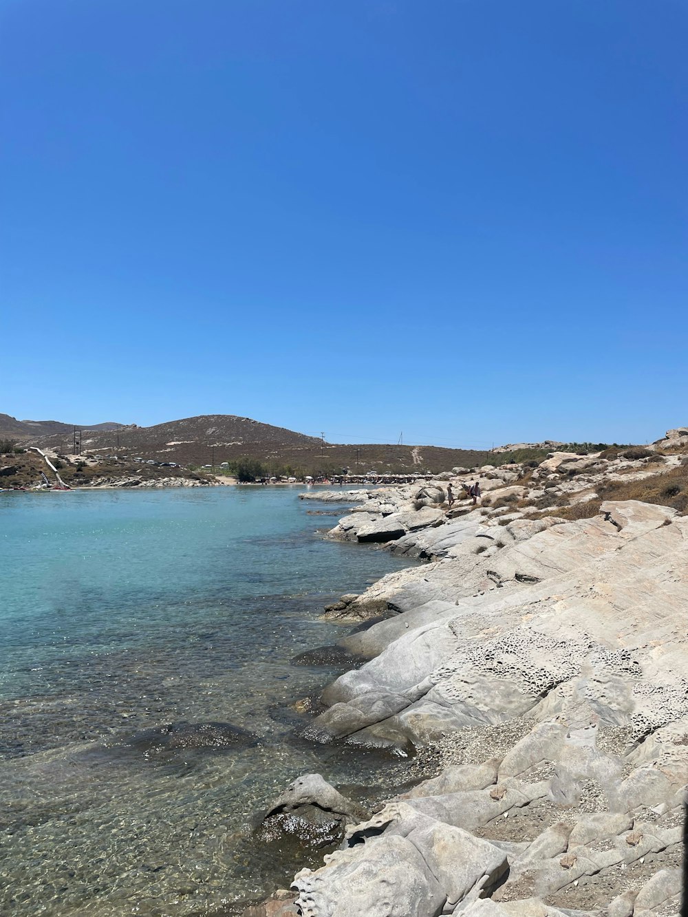 a rocky beach with a body of water in the background