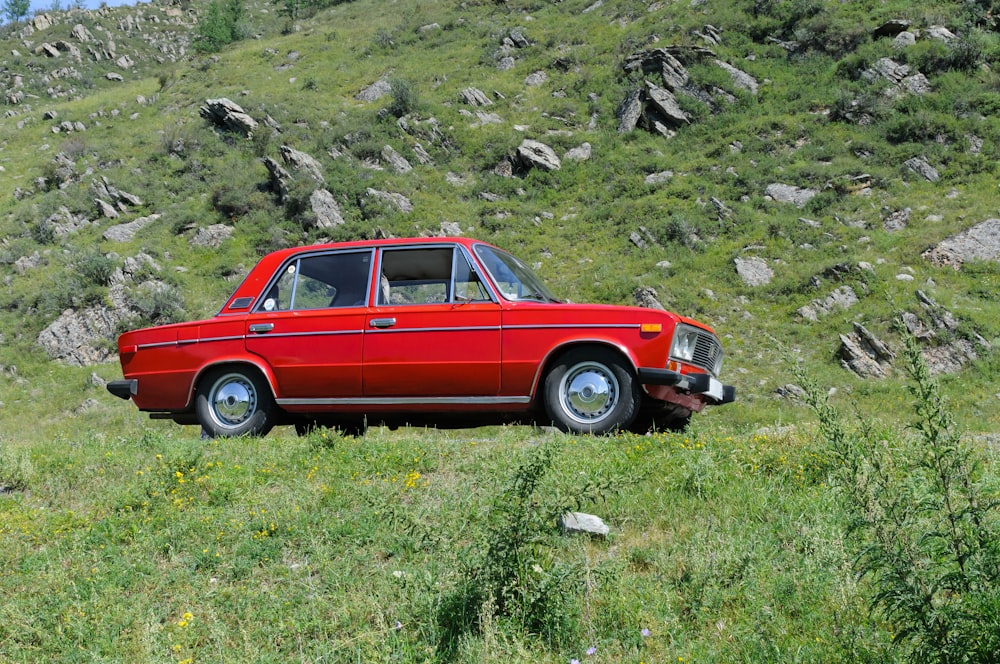 a red car parked on a rocky hillside