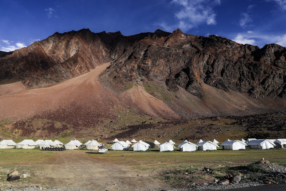 a group of white tents in front of a rocky mountain