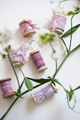 Hand-painted yarn bobbins with floral designs resting on a wooden table.