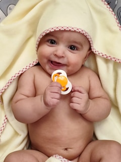 A joyful newborn baby wrapped in soft blanket during a studio photo session.