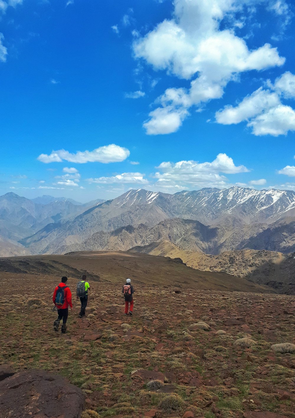 Un grupo de personas caminando por un camino de tierra frente a una cordillera