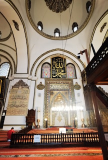 The interior of a mosque showcasing stunning calligraphy and chandeliers.