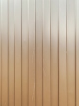 Vertical metal panels with evenly spaced groves running from top to bottom. The surface is slightly reflective with some visible scratches and lines.