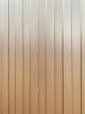 Vertical metal panels with evenly spaced groves running from top to bottom. The surface is slightly reflective with some visible scratches and lines.