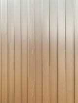 Vertical metal panels with evenly spaced groves running from top to bottom. The surface is slightly reflective with some visible scratches and lines.