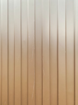 Vertical metal panels with evenly spaced groves running from top to bottom. The surface is slightly reflective with some visible scratches and lines.