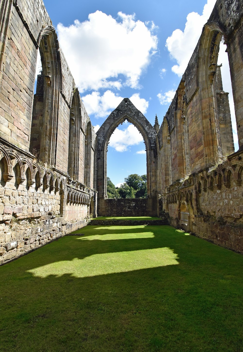 a stone archway over a grass field with Sweetheart Abbey in the background