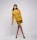 A fashionable model poses confidently wearing a mustard yellow blazer and shorts. She is accessorized with a knitted brown hat and black shoes, set against a minimalist gray background.