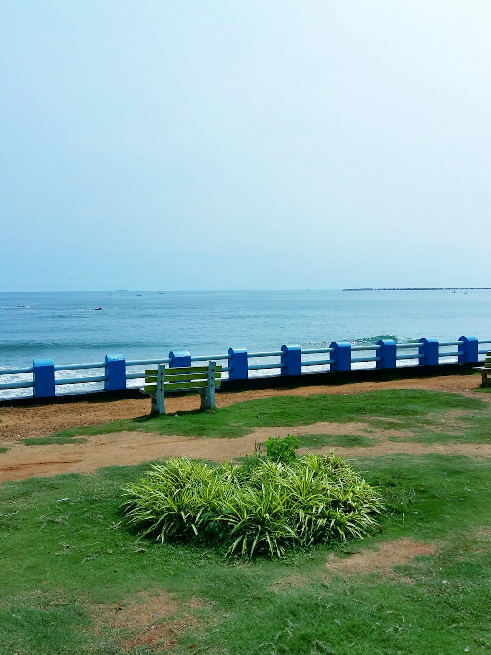 a row of blue benches next to a body of water