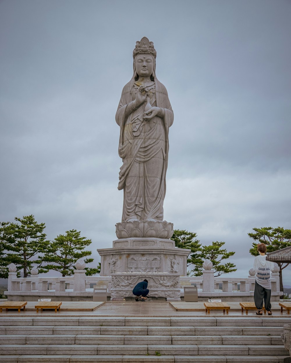 a statue of a person with National Monument to the Forefathers in the background