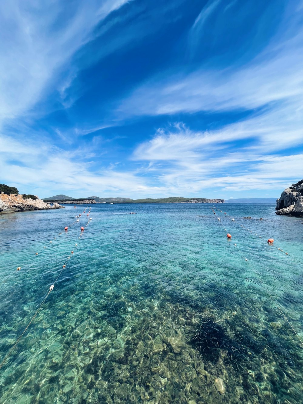 a body of water with rocks and land in the background