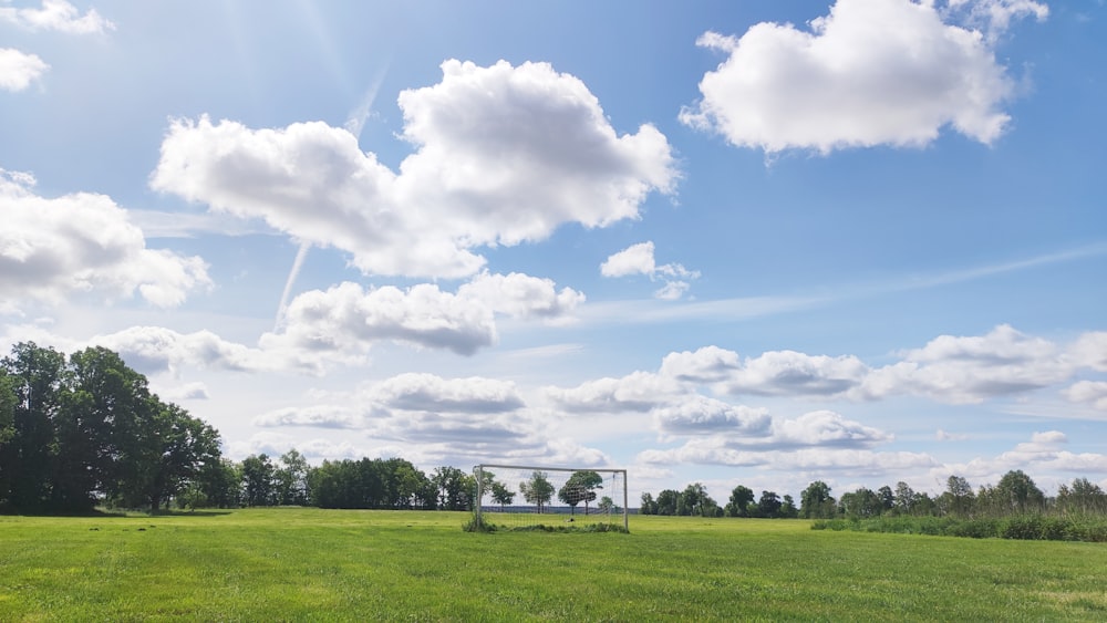 a grassy field with a goal and trees in the background