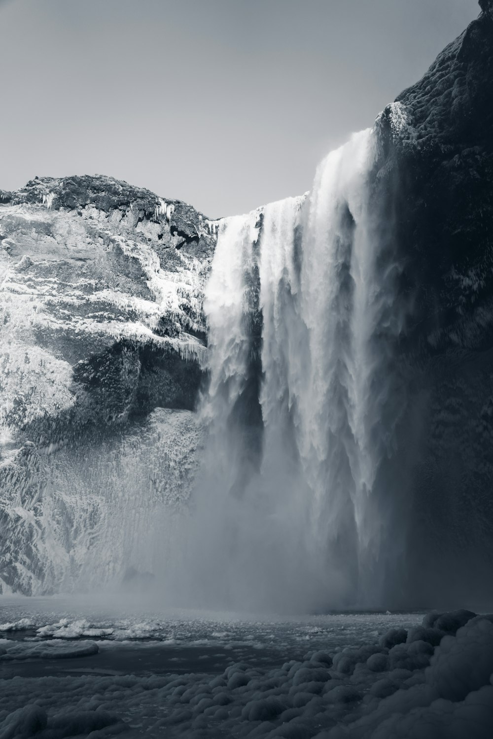 a waterfall with rocks and a body of water below