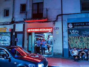 A vibrant street-style fast food restaurant entrance glowing with red LED lights at night.