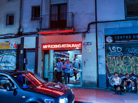 A vibrant street-style fast food restaurant entrance glowing with red LED lights at night.