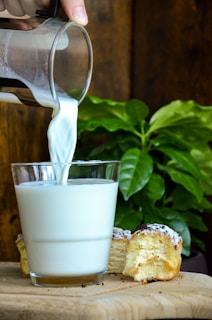 a glass of milk being poured into a cup of milk