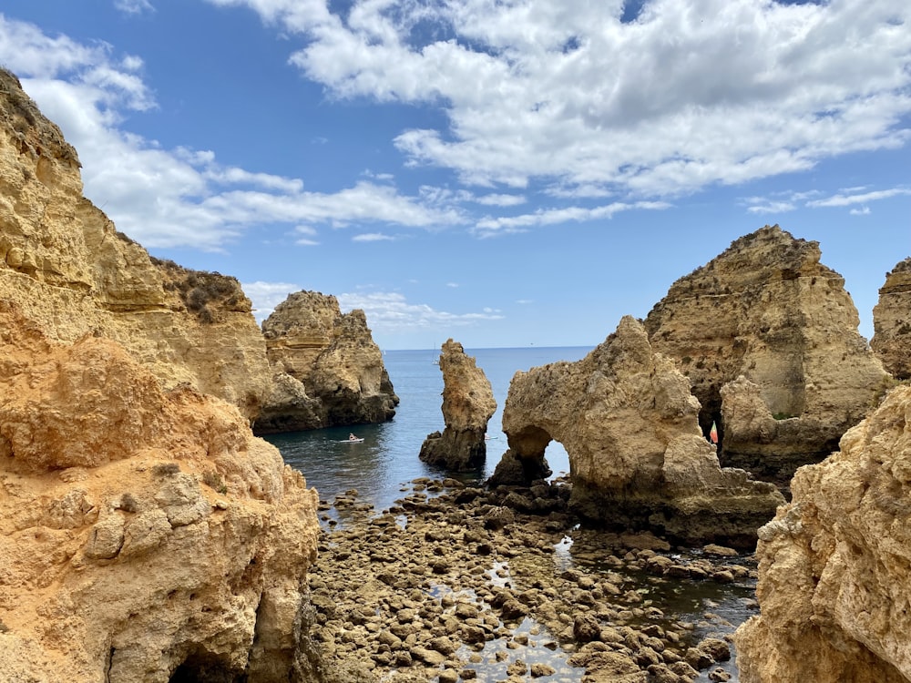 uma praia rochosa com um corpo de água no fundo