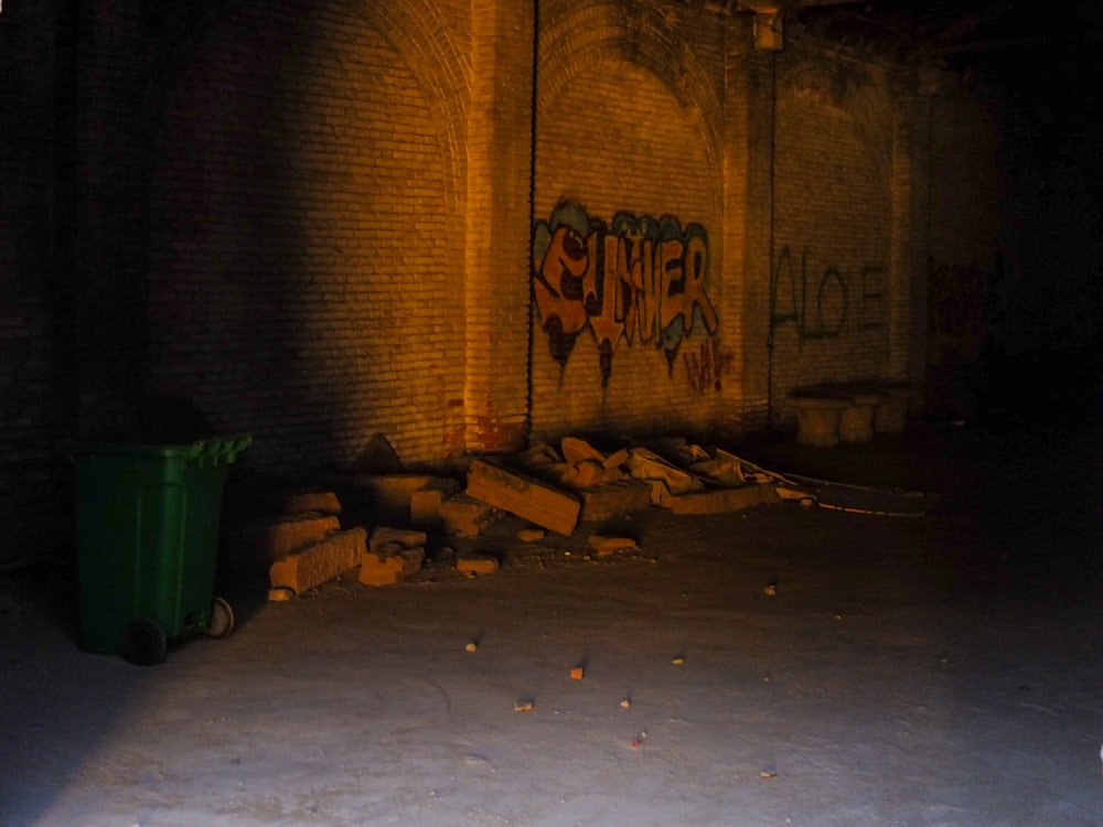 a trash can next to a wall with graffiti