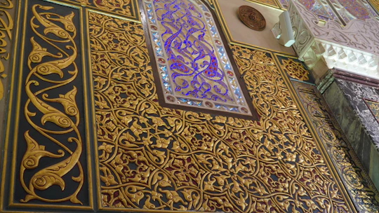 Close-up of intricate arabesque motifs softly glowing with gold gradients on a dark green background.