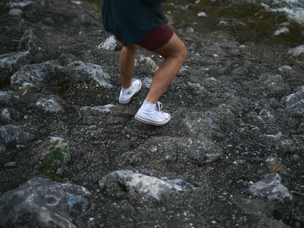 a person's legs and feet on a rocky surface