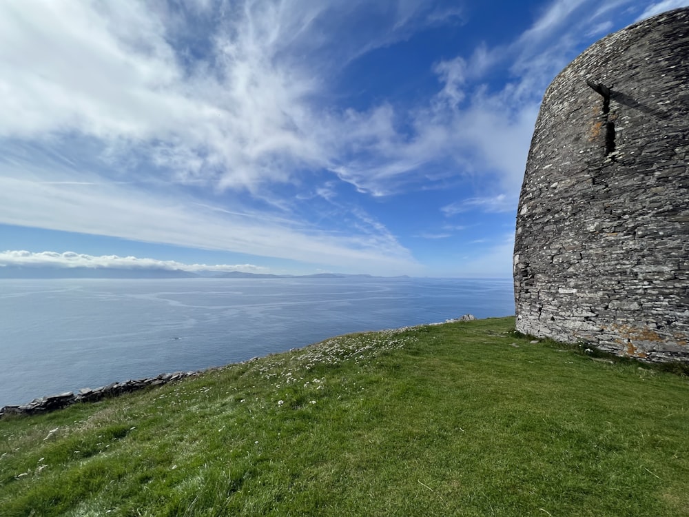 a stone wall on a grassy hill overlooking the ocean