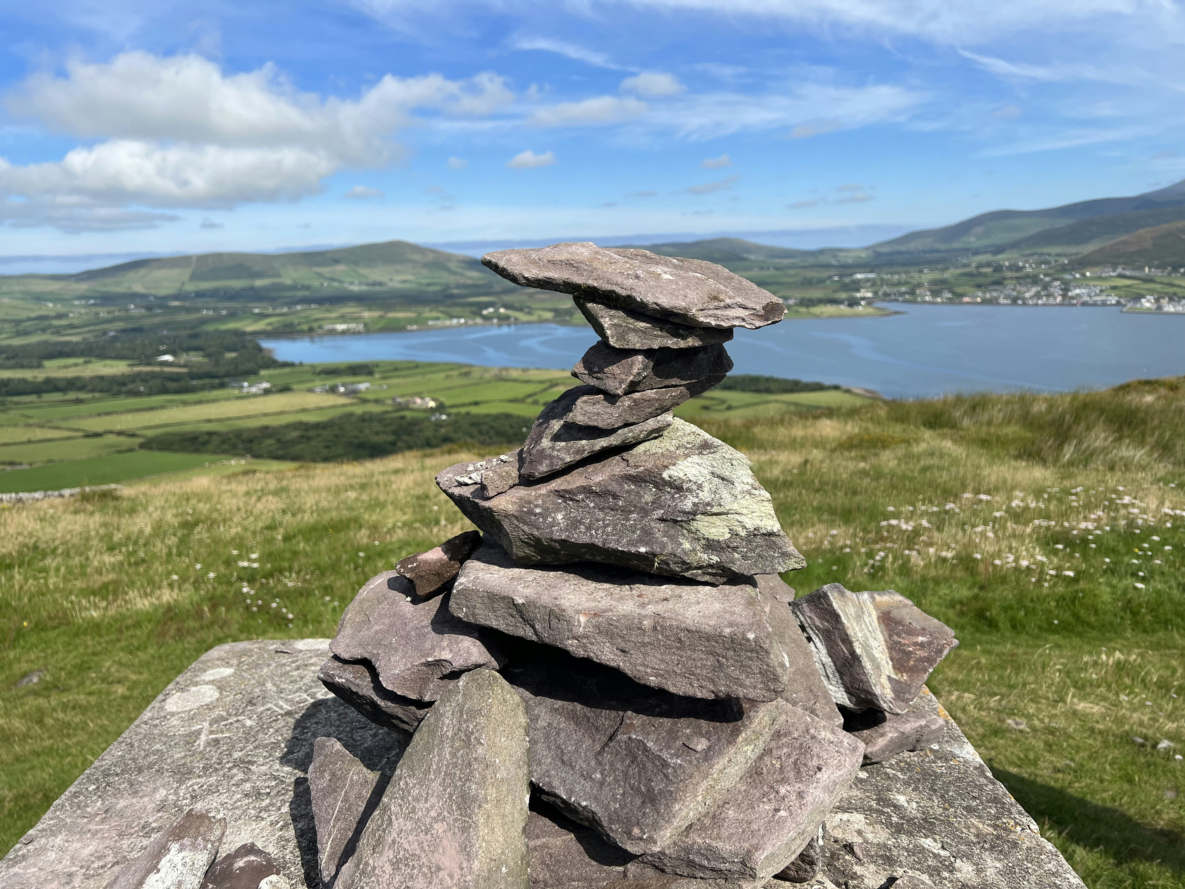 a large rock on a grassy hill overlooking a body of water