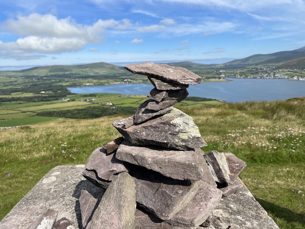 a large rock on a grassy hill overlooking a body of water