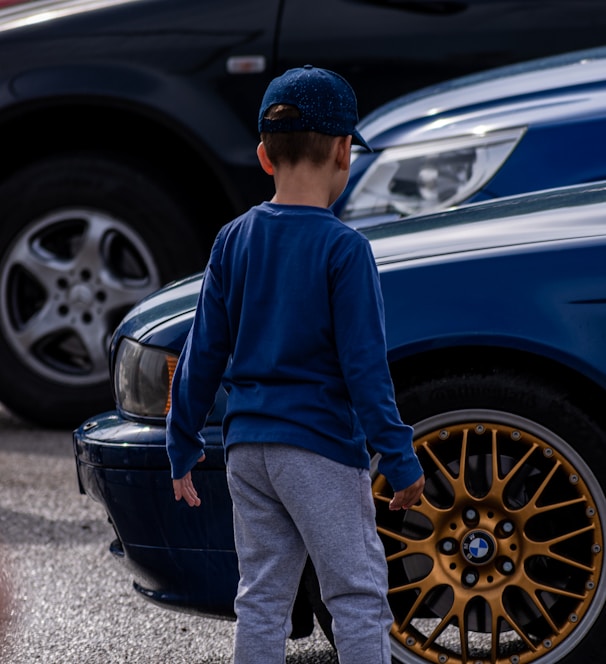 a boy standing next to a car