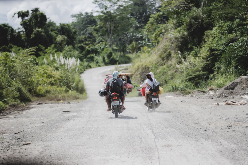 a group of people ride motorcycles down a dirt road