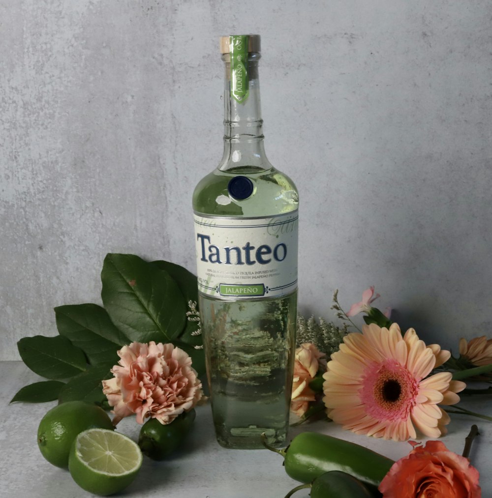 a bottle of alcohol next to some flowers