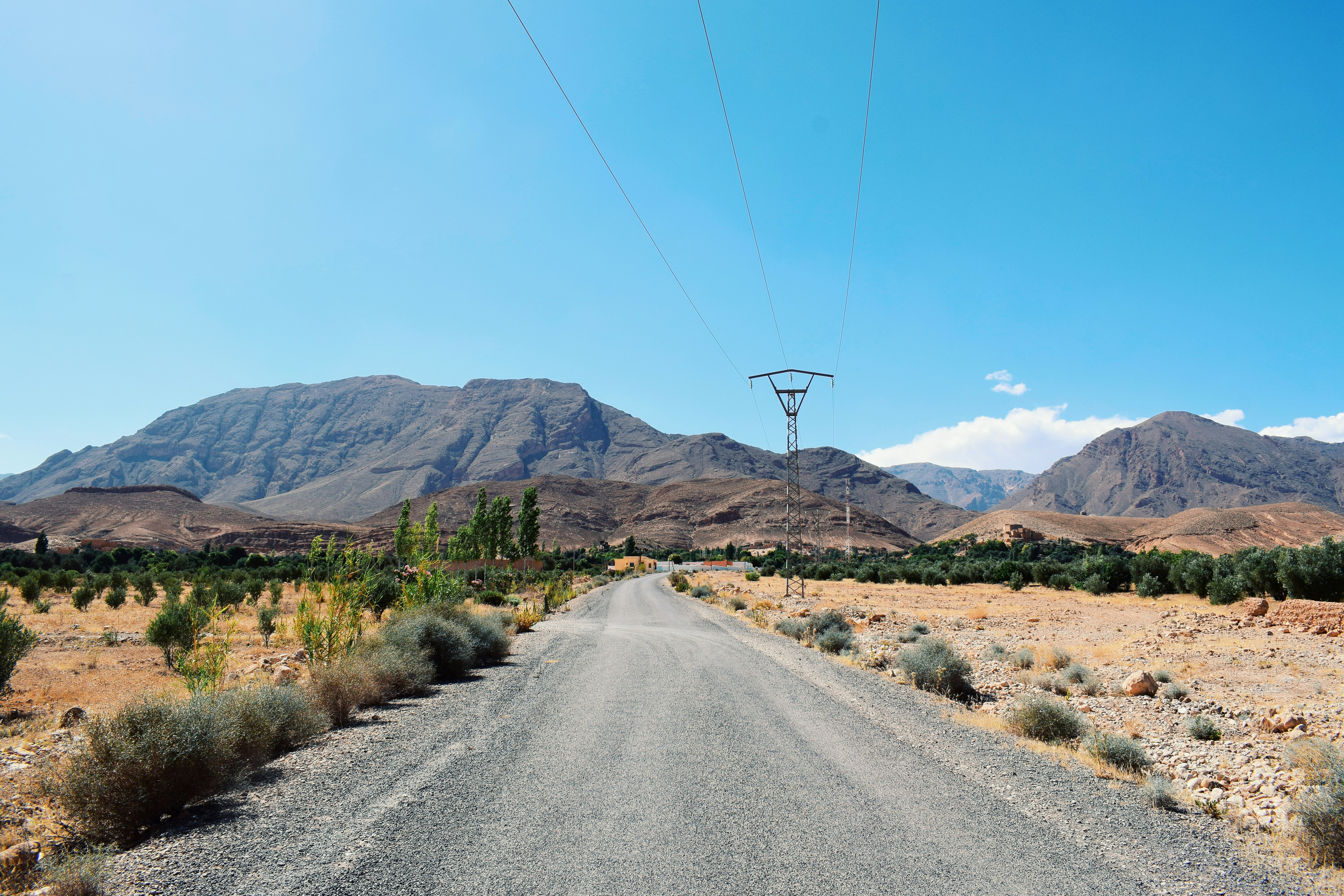 a road with mountains in the background, A small village called Outat el haj located deep Morocco