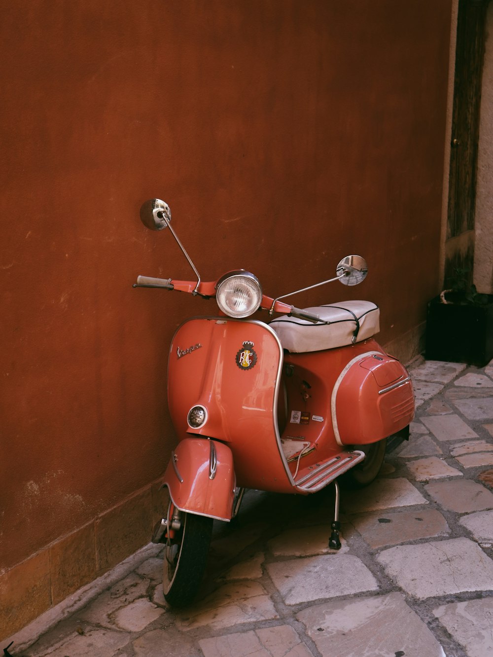 a red scooter parked on a brick sidewalk